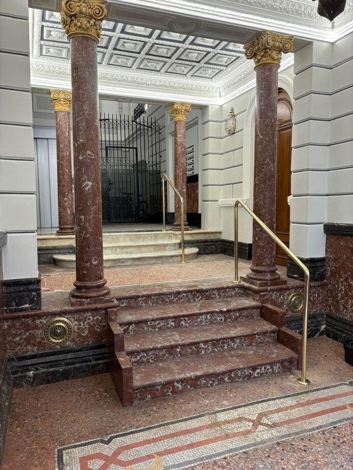 Pasamanos de latón en portal clásico con columnas de mármol en Madrid