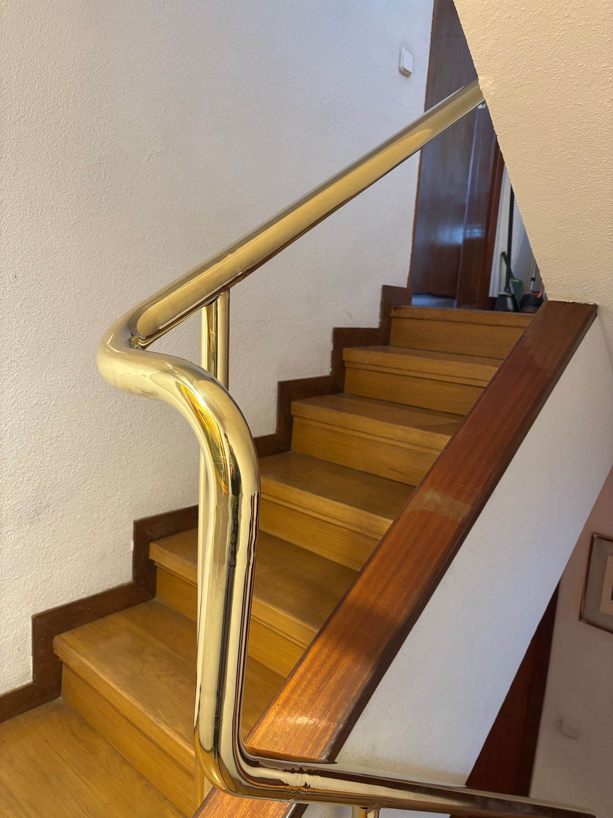Pasamanos de latón curvado a medida en escalera de madera